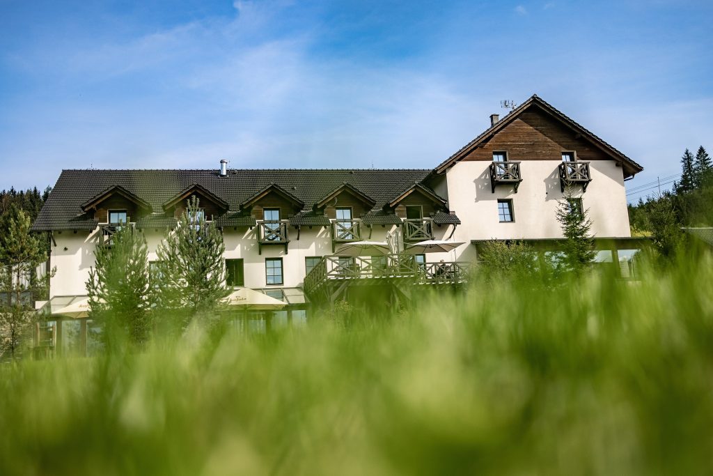 Horský hotel Kempa s dřevěnými balkony a terasou v zeleni