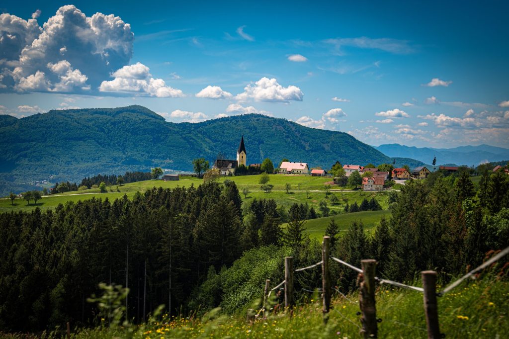 Zelené kopce a vesnička s kostelíkem v klidné krajině východního Slovinska