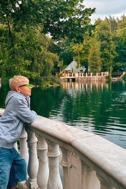 Chlapec u zábradlí sleduje jezírko s fontánou v parku lázní Rajecké Teplice